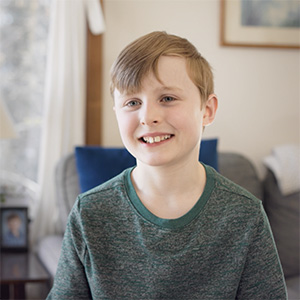 Portrait of Kellen Malley, a young boy smiling in a green shirt